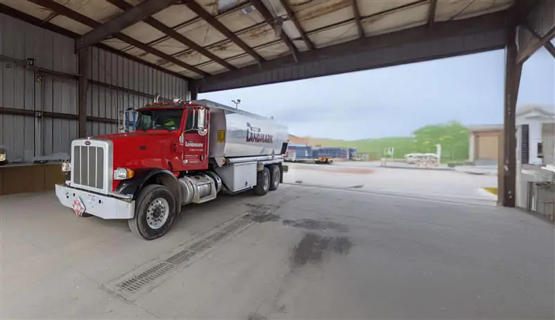 Red and silver Landmark fuel delivery truck parked under a large metal canopy, featuring a chrome grille and tandem rear wheels with the company’s logo displayed on the tanker.